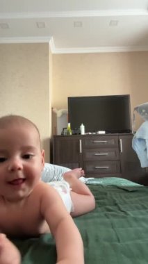 Sevimli bebek öğrenimi yatakta tatlı bir yüzle sürünüyor.