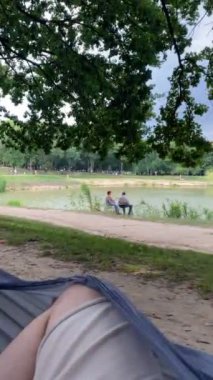 Pov adam hamakta dinleniyor. Diğer hamakta bebekle annesine bakıyor.