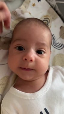 Uzanan bir bebeğin yakın çekimi, merakla onları işaret eden bir parmağa bakıyor..