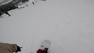 Bir snowboardcu karlı bir yamaçtan aşağı iniyor, ağaçlar kenarlarını kaplıyor..