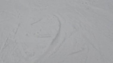 Bir snowboardcu karlı bir yamaçtan aşağı iniyor, ağaçlar kenarlarını kaplıyor..