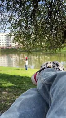 Anne gölü kıyısında bir hamakta dinlenirken arka planda bebek var.