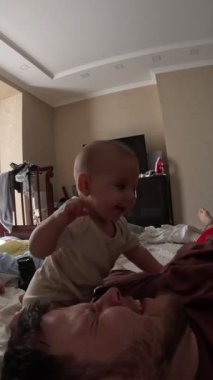 Bebek, babayla yatakta şakalaşıyor. Yakın çekim.