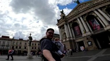 Baba ve bebek şehir meydanında selfie çekiyorlar.