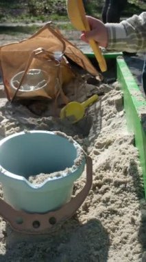 Güneşli bir günde Sandbox 'ta oyuncaklarla oynayan bir çocuk.