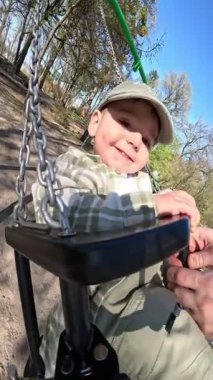 Yürüyen çocuk güneşli bir parkta salıncağın tadını çıkarıyor.