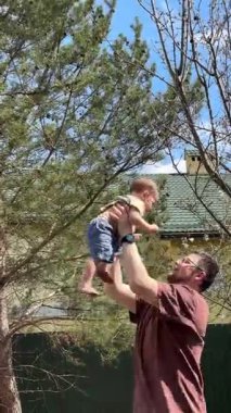 Güneşli arka bahçede çıplak ayakla oynayan neşeli baba ve çocuk.