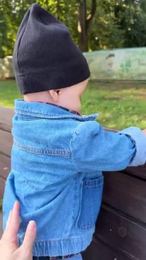 Denim Outfit 'teki bebek ahşap bankta ayakta durmayı öğreniyor