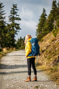 Sırt çantalı bir kadın dağlarda yürüyüş yapıyor. Spor kıyafetleri giyen bir kadın yürüyüşçü.