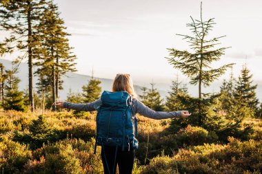 Sırt çantalı bir kadın dağlarda gezmekten zevk alıyor. Doğadaki macera. Kollarını açmış kadın turist.