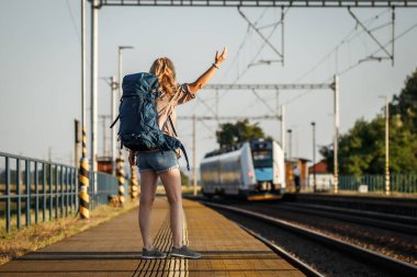 Hayal kırıklığına uğramış gezgin tren istasyonunda treni kaçırdı. Sırt çantalı kadın turist yalnız seyahat ediyor.