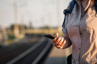 Akıllı telefonunda cep telefonu uygulaması olan bir kadın tren bileti alıyor.