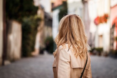 Trençkot giyen ve şehir caddesinde yürüyen şık bir kadın. Moda tarzı