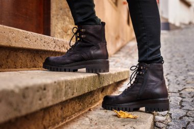 Modaya uygun siyah deri çizmeler. Yakın plan şık ayakkabılar. Sokakta yürüyen kadın bacakları.