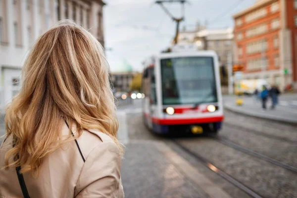 Tramvay bekleyen bir kadın. Şehre gelen tramvaya bakan bir yolcu. Toplu taşıma