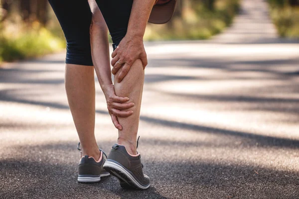 여자는 조깅을 다리에 통증을 느낀다 경련을 멈춰라 달리기를 운동을 과소평가 스톡 사진