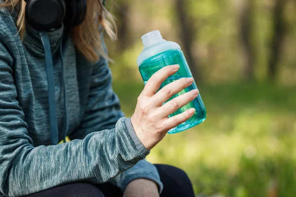 Şişeden su içen susamış kadın. Ormanda koşarken ve koşarken dinleniyor. Spor ve spor aktiviteleri
