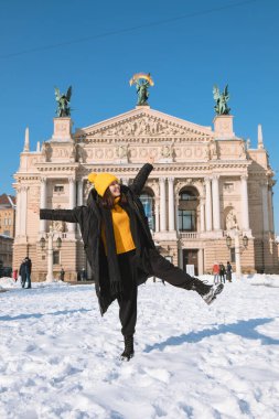 Lviv şehrindeki opera binasının önündeki mutlu kadın gezgin kış mevsimi kar yağdı