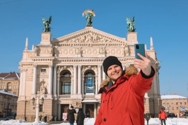 Gülümseyen adam Lviv City Ukrayna 'nın opera binasının önünde selfie çekiyor.