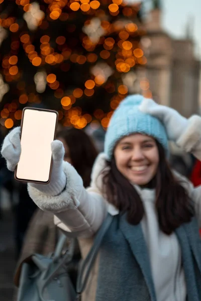 Улыбающаяся Счастливая Женщина Рождественской Городской Ярмарке Держит Телефон Белым Экраном — стоковое фото