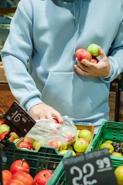 一个男人买食物 一位男性顾客选择苹果 从商店的货架上取货 — 图库照片