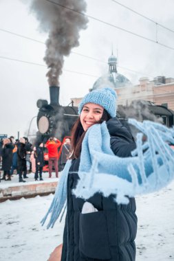 Tren istasyonunda gülümseyen kadın portresi. Eski buharlı trenin yanında kış zamanı.