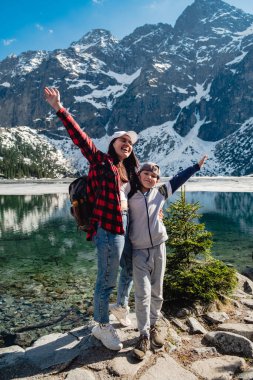 Mom with son are standing on the shore of a lake. Morskie Oko, Tatras mountains. Poland
