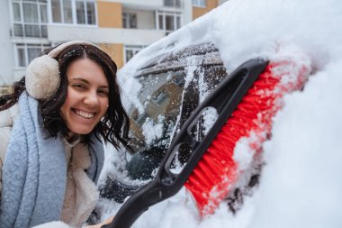 Kış yaklaşıyor, kar yağışı bekleniyor. Kadın kardan araba temizliyor.
