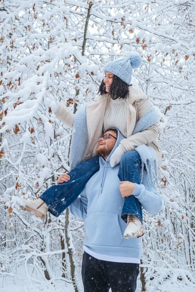 A woman rides on mans shoulders in snowy forest