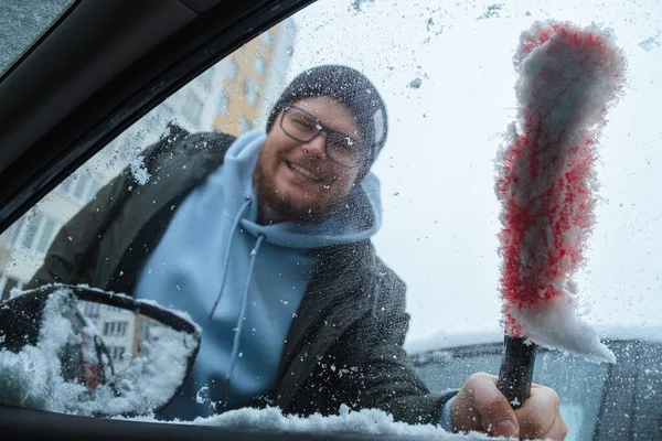 Snowfall is forecast for winter months, and man cleans car from snow