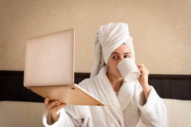 Kafasında havluyla beyaz geceliğiyle evde çalışan bir kadın.