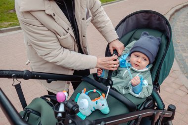 Anne oğlunu bebek arabasında emniyet kemerleriyle bağlayacak.