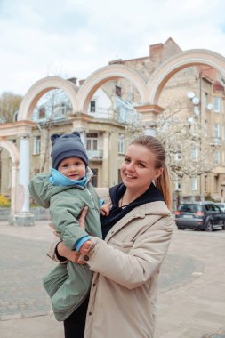 Mutlu anne halka açık parkta bebeği kollarında tutuyor.