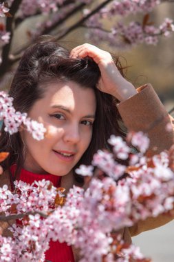Çiçekli sakura ağacında fotoğraf çeken kadın geliyor.
