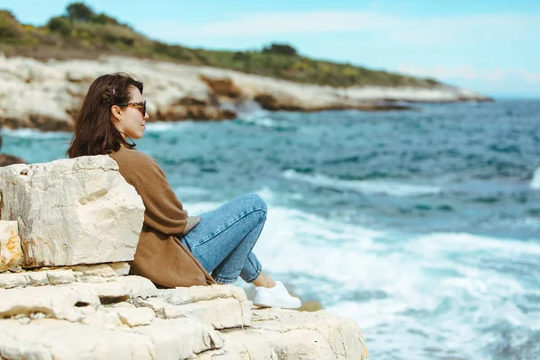 Uçurumun Kenarında Oturup Deniz Manzarasının Keyfini Çıkaran Kadın Rüzgarlı Hava — Stok fotoğraf