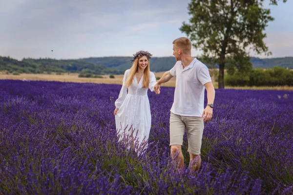 a couple in love is walking in a lavender field. cloudy sky