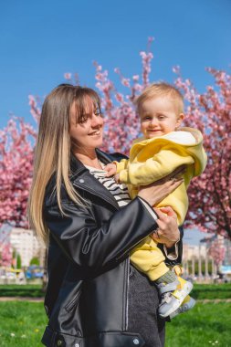 Pembe kiraz çiçeklerinin yanında baharın tadını çıkaran bir anne ve oğul..