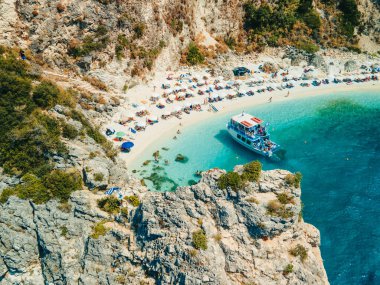 Mavi mayo giymiş mutlu bir kadın, Lefkada adasının tepesinde Yunan bayrağı taşıyor.