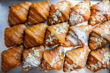 Badem gevreği ve pudra şekerli kruvasanları fırına serp.