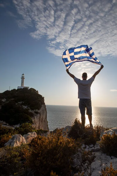 Mężczyzna Grecką Flagą Patrząc Zachód Słońca Nad Morzem Lefkada Latarnia — Zdjęcie stockowe