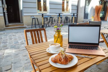 Kafede kruvasan ve kahveyle bağımsız çalışanlar.