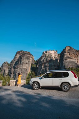 Cip 'in yanındaki kadın, Yunan dağlarındaki meteora manastırının fotoğrafını çekiyor.