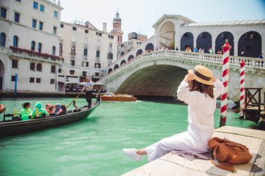 Venedik 'te rialto köprüsünün yanında oturan kadın gondollu Grand Canal' a bakıyor.