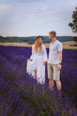 Birbirine aşık bir çift lavanta tarlasında yürüyor. bulutlu gökyüzü