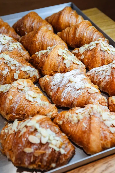 stock image Sprinkle finished croissants on baking sheet with almond flakes and powdered sugar