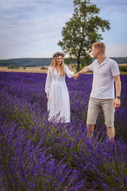 Birbirine aşık bir çift lavanta tarlasında yürüyor. bulutlu gökyüzü