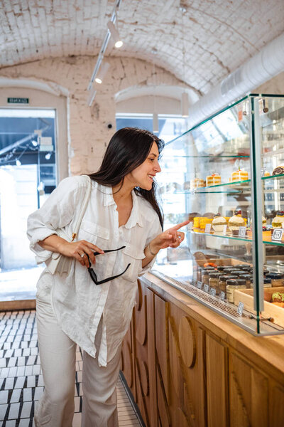 woman chooses cake from window in a coffee shop