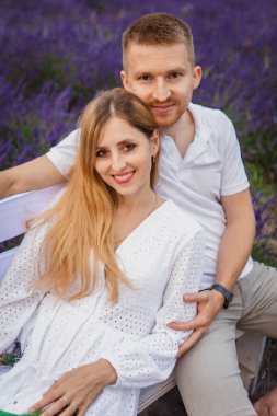 Lavanta tarlasında, mutlu bir çift bankta oturur ve birbirlerine sarılırlar.