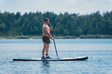Adam gölün ortasında ayakta duruyor. Yaz su aktiviteleri.