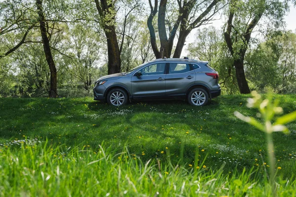 stock image a gray car parked on a green lawn